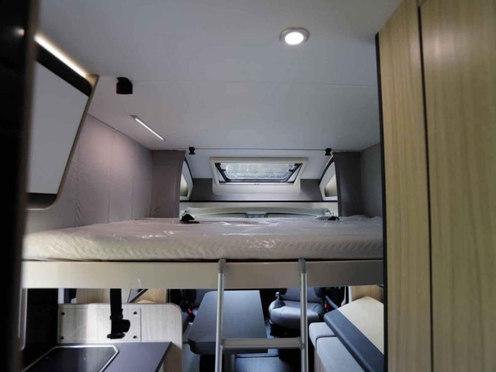 Dinette van de Sun Living S72DL camper met het hefbed in neergelaten positie erboven, waardoor er extra slaapruimte ontstaat boven de zithoek